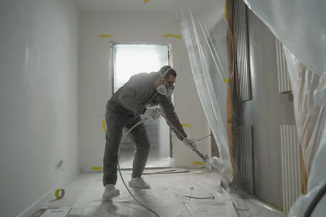 A worker in protective gear painting walls during an indoor renovation project. More referrals for a mold remediation business: what actually works